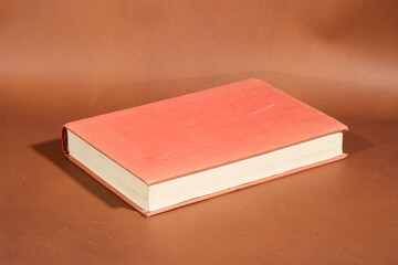 Book with Red Cover on Brown Surface
