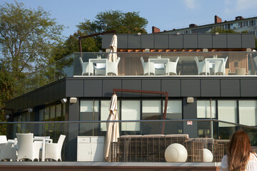 A fragment of a two-story restaurant building with tables for visitors on the balcony. Restaurant furniture made of synthetic rattan.