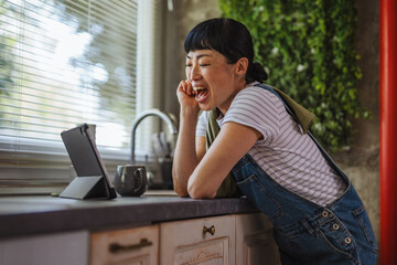Japanese woman watch tablet while take a break from wiping in kitchen