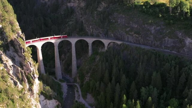 Landwasser Viaduct of the Rhaetian Railway, Filisur, Canton of Grisons, Switzerland, Passenger train crossing the Landwasser Viaduct in the Swiss Alps, red train on the railway. Unesco World Heritage