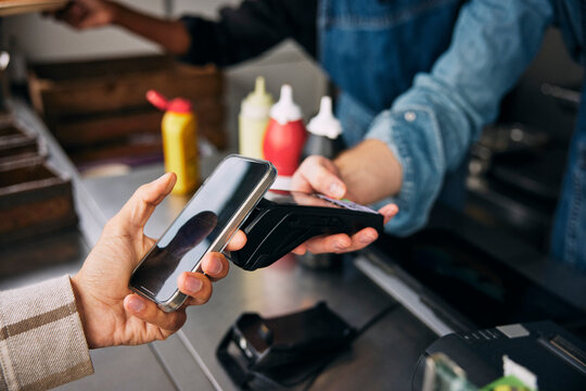 Hand of man paying through tap to pay method on credit card reader at food truck