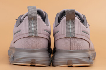 Stylish athletic footwear in soft pink color with gray accents on neutral background