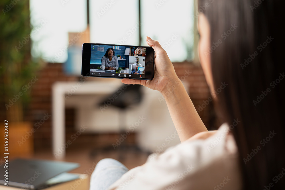 Poster female entrepreneur using cellphone for team video conference, having digital briefing. close up of 