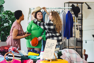 Girls having fun at home swap party. Garage sale, second hand, trying used clothes, exchanging...
