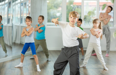 Boy with friends repeat teaches sequences of movements during training, train to perform electro dance, enjoys active hobby to her favorite music. Unrecognizable female teacher administer conduct