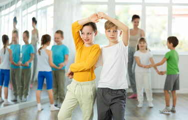 Positive preteen children learning to dance waltz in pairs in choreography class