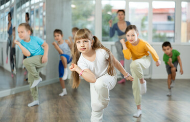 During dance workshop, girl with team of young like-minded children learn to dance hip hop dances,...