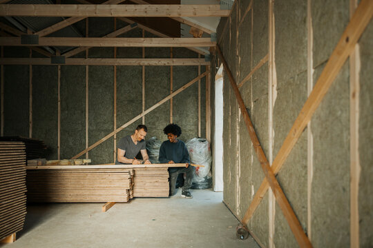 Father teaching son to mark measurements on wooden plank at renovation site
