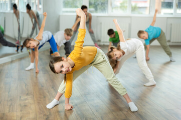 Obraz premium Girl learns to dance hip hop during childrens master class in studio. Teacher watches students, participates in training