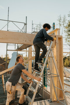 Father helping son climbing on ladder in back yard during home construction