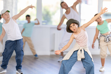 Portrait of confident tween girl hip hop dancer training during group dance class in modern dance...