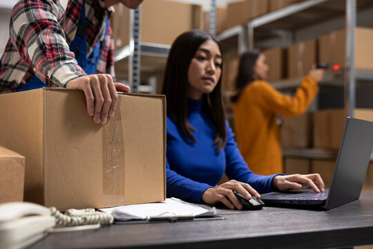 Asian depot team packing boxes at packaging station for small business, managing orders for the local brand in warehouse. Employees prepare merchandise for growing distribution hub.