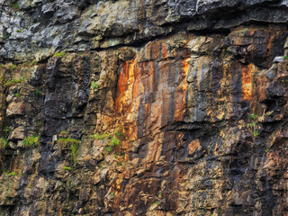 A rock wall with a lot of rust and cracks. The wall is made of stone and has a lot of texture....