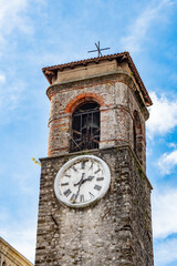 view of the historic church bell tower in Faedis, Italy, featuring a traditional clock face and...