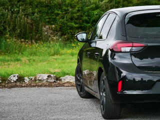 Black cark parked by a green area in a park, travel and tourism industry.