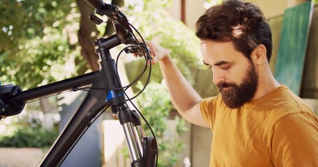 Sports-loving male loosening and removing damaged wheel from bike front fork with expert multitool...