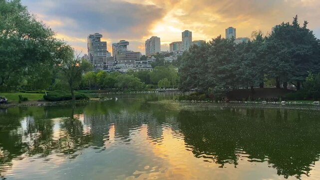 Lake park view and behind modern buildings silhouette at sunset in Istanbul, Turkey. (4K video)