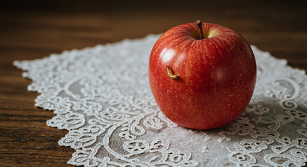 Red apple on lace doily placed on wooden table  