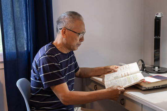 senior man learning new language, reading book with exercises