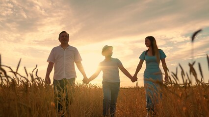 Father mother child son walking together holding hands enjoying nature. Mother father boy walking in wheat field. Farmer family with teenage boy walking in wheat field. Child son parents travel nature