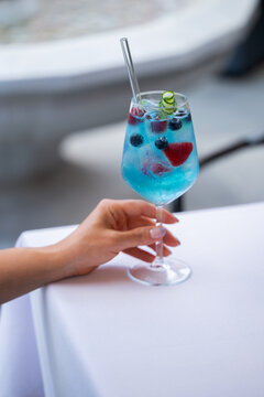 Hand holding summer cocktail with curacao and fruits outdoors