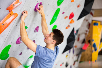 Fototapeta premium Sporty man training at bouldering gym without special climbing equipment