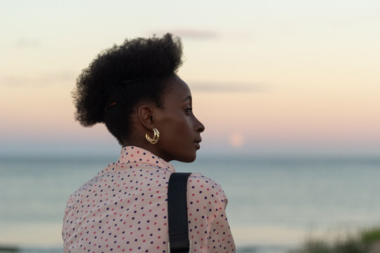 Stylish woman watching sunset at beach