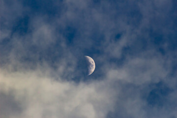 The moon in the clouds on a clear day, view from below