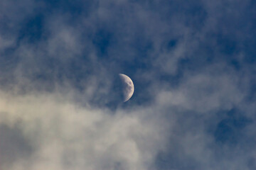 The moon in the clouds on a clear day, view from below