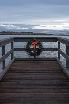 Christmas wreath with red ribbon on the ocean pier