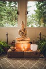 Buddhist altar with candles, plants and a huge Buddha in the center.
