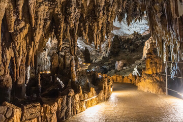 Stalactites hanging from ceiling in illuminated cave with walking path, Skocjan cave, Slovenia