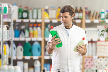 Man choose product and doubts, faultfinding buyer pick shower gel for allergy sufferers and...