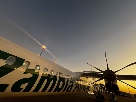 An aircraft at sunset with visible propellers at Harry Mwanga Nkumbula International Airport in Livingstone, Zambia
