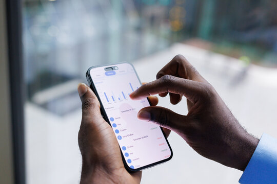 Anonymous black man looking through charts on screen of smartphone