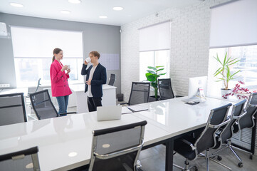 Colleagues sit drinking coffee and talking during a break at work. 