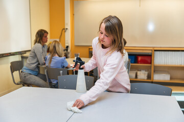 Student Cleaning Desk in Classroom