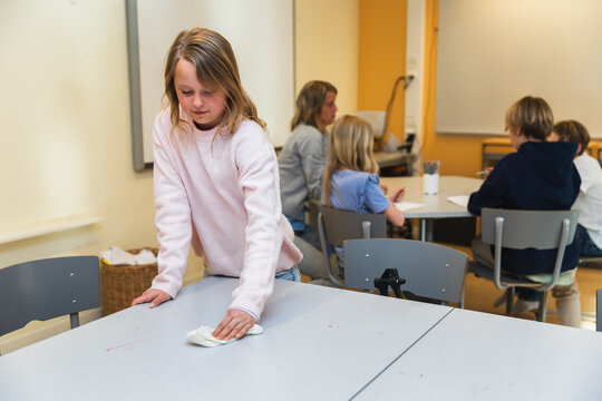 Girl Cleaning Table in Classroom