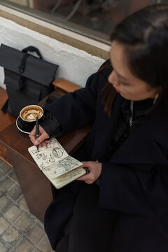 Woman drawing sketches in notebook at cafe