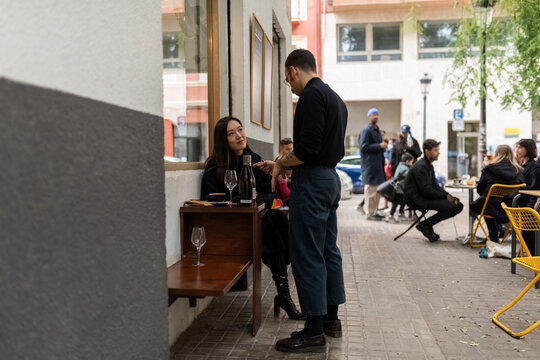 Woman listening to waiter explaining wines for tasting