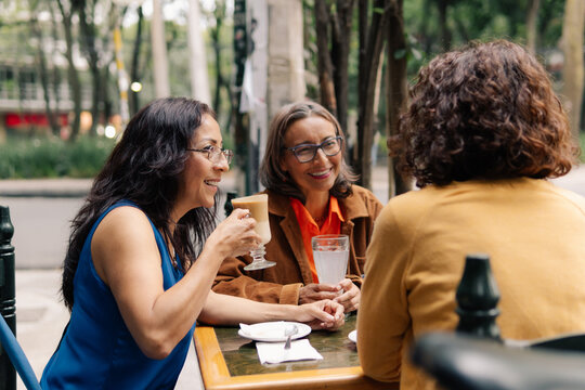 Three  women enjoy coffee at a coffee shop.