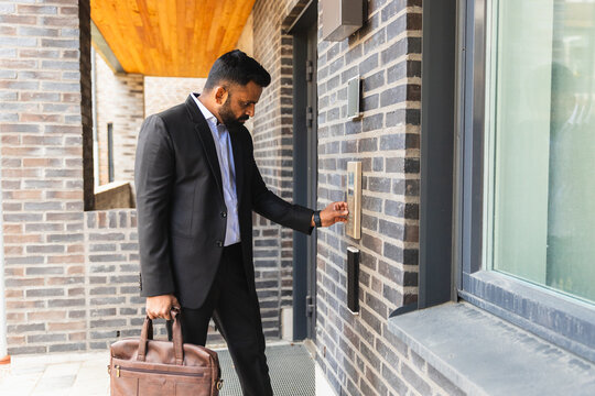 Businessman Using Intercom at Building Entrance