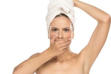 Young woman with hand over mouth looking shocked, studio shot on white background