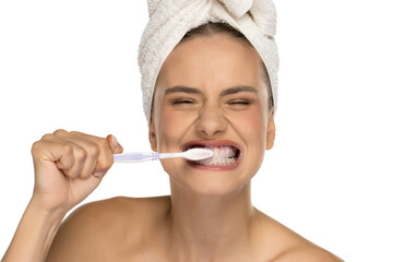 Young woman brushing teeth with exaggerated expression, eyes closed, studio shot on white background.