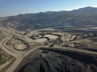 Heavy quarry dump trucks carry coal in their backs.