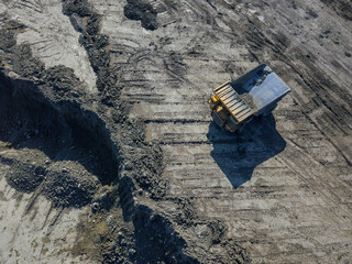 Heavy quarry dump trucks carry coal in their backs.