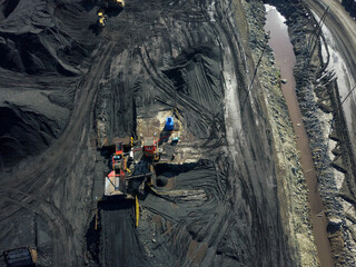 Heavy quarry dump trucks carry coal in their backs.