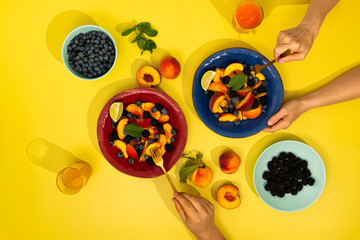 A vibrant fruit salad with human hands