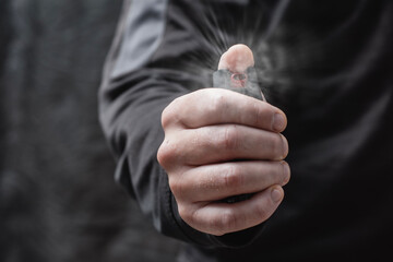 Close-up of a man hand pressing a pepper spray canister with visible aerosol release. Concept self-defense, protection, danger prevention, and personal safety.