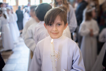 boy before first Eucharist in a catholic church. child in white clothes with a candle in the church